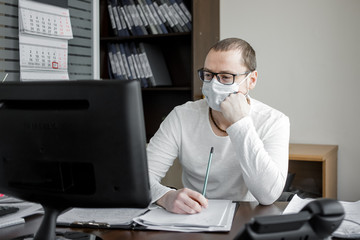 Businessman sit at desk in office wearing a face mask