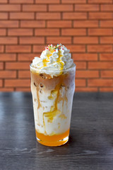 Orange iced coffee latte in glass on wooden table