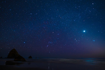 Night beach of the sea or ocean at sunset. Rocks in the water. Night night sky.