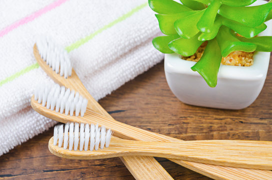 Bamboo toothbrushes in glass with towel.