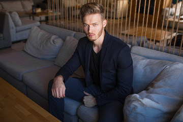 Fototapeta premium successful beautiful young man blond is located in a modern loft room, hookah.
