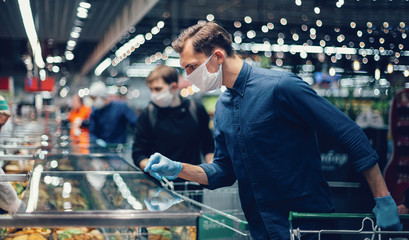 customer in protective gloves looking at the products in the refrigerator