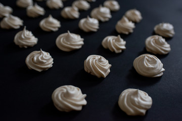 A popular French meringue dessert on a black background. Side view