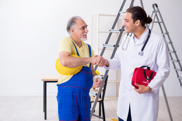 Young male doctor and old contractor in first aid concept