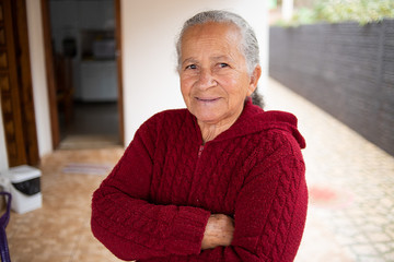 Retrato da mulher idosa de sorriso bonita com cabelo branco e braços cruzados e expressão alegre.
