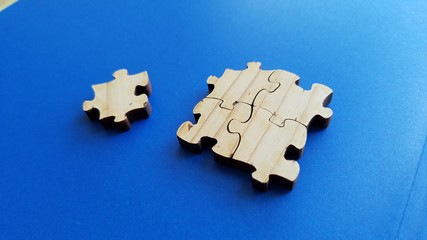 Obraz premium Wood surface puzzle pieces close up view on clean blue background, concept of isolation