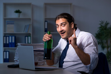 Alcohol addicted businessman working late in the office