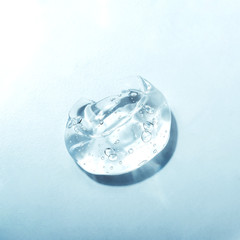 Texture of hyaluronic acid, serum gel. Transparent smear of gel isolated on blue background