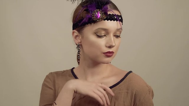 Girl in the 90s style, chicago style. Hat, headband with decorative feathers on the head. Incredible jewelry, long earrings with diamonds, coquette. dance and pouse