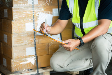Worker courier holding clipboard writing on checklist for delivering shipment pallet goods. Package boxes, packaging, cargo export, industry warehouse shipping logistics and transport. 