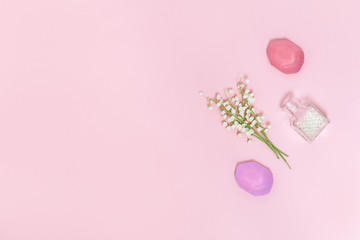 Flowers of lilies of the valley and fragrant soap on soft pink background with free space for text. Handmade soap bars. Aromatherapy, beauty spa background. Top view.