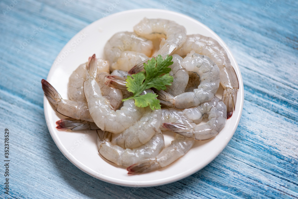 Wall mural fresh shrimps or prawns , seafood shelfish - raw shrimp on white plate and wooden background for coo