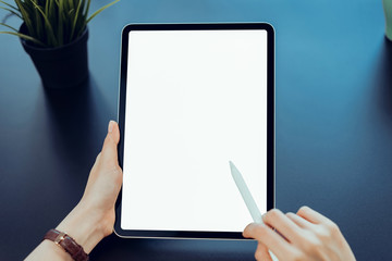 Closeup of woman hand holding digital tablet on the table and the screen is blank.
