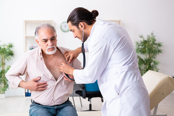 Obraz premium Old man visiting young male doctor cardiologist