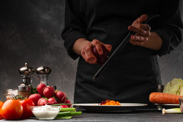 Chef rubs beets for cooking. Against the background of vegetables and ingredients. Cooking tasty...