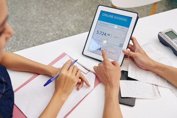 Small business owners discussing debt to the bank they need to pay when checking bank account via application on tablet computer