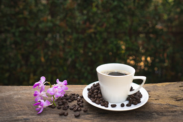 Cup coffee, wild fragrance orchid and roasted coffee bean on wooden table.