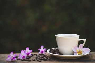 Cup coffee, Phaleanopsis  and roasted coffee bean on wooden table.