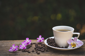 Cup coffee, Phaleanopsis  and roasted coffee bean on wooden table.