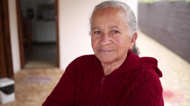 Retrato da mulher idosa de sorriso bonita com cabelo branco e bra&ccedil;os cruzados e express&atilde;o alegre.