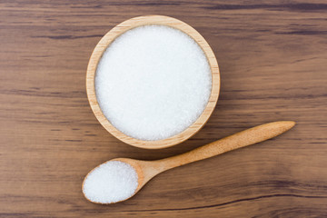 Monosodium glutamate ( MSG ) in wooden bowl and spood isolated on  rustic wooden table background. Top view. Flat lay.
