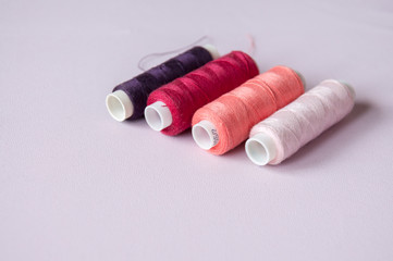 Sewing reinforced threads of different colors on a pink background