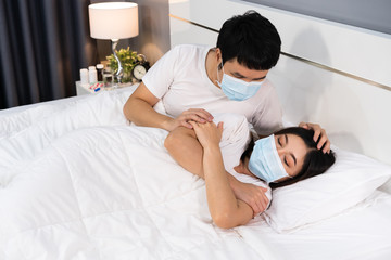 Obraz na płótnie Canvas man taking care of his sick wife on bed at home, couple wearing medical mask for protection coronavirus (covid-19) pandemic