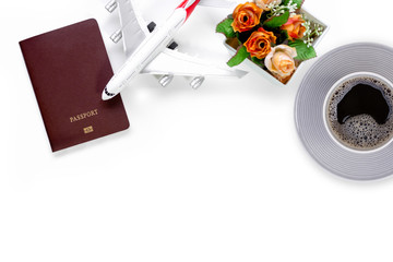 Business trip and travel concept. Airplane miniature, boarding passport book, flowers and cup of coffee isolated on white background with copy space for text and content. Top view. Flat lay.
