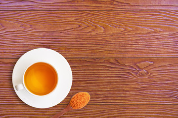 Closeup ceramic cup of hot Turmeric tea with tumeric powder in wooden spoon isolated on wood table background . Healthy drinks and health food boost immune system concept. Top view. Flat lay.