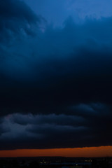 Obraz premium Black thunderclouds at sunset. Bright orange sunset and dark clouds. Storm sky