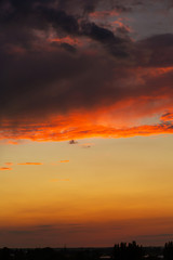 Black thunderclouds at sunset. Bright orange sunset and dark clouds. Storm sky