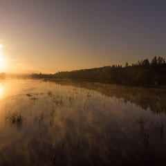 Dawn on the lake, with steam in the forest. Morning landscape, with the rays of the sun. Shot from a height