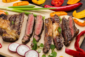Fresh grilled meat. Grilled marbled beef steak medium rare with vegetables on wooden cutting board. 