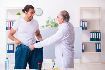 Doctor dietician and happy patient wearing large trousers