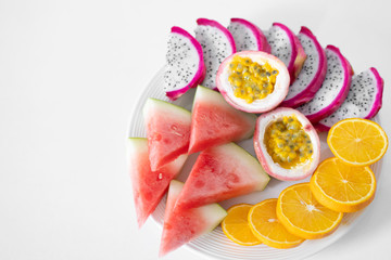 White plate of sliced fruit. Fresh fruits and vitamins. Still life colored summer fruits.