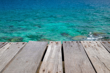 Old wooden platform beside the sea. Wood deck with blue ocean background.