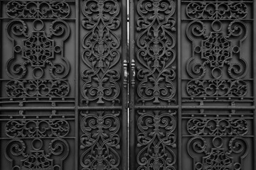 Black iron forged gate in front of the house. Classic ornamental forged metal double gates.