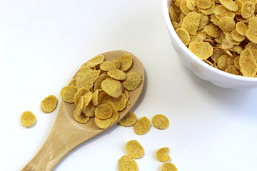 Dry breakfast corn flakes on a wooden spoon