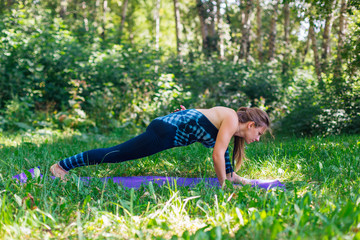 Fototapeta premium Young woman doing yoga exercises in summer city park.