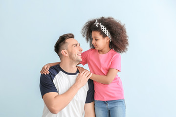 Happy man with little adopted girl on color background