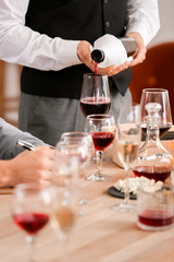 Waiter pouring wine in glass at the restaurant