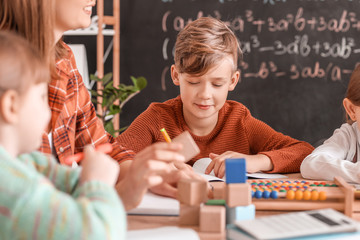 Children with math teacher during lesson in classroom