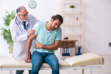 Fototapeta premium Injured young man visiting old doctor