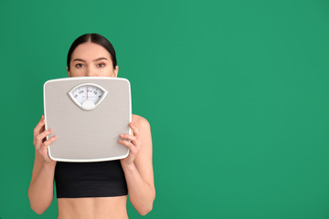 Young woman with measuring scales on color background