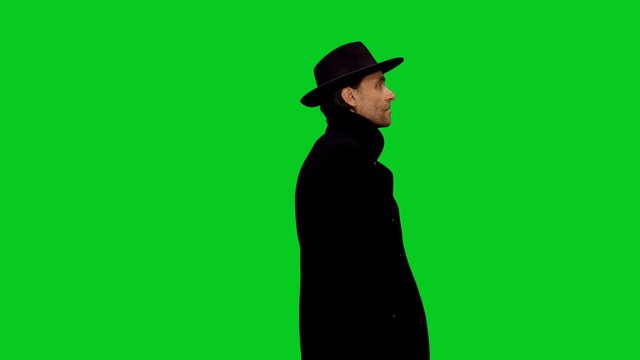 Rear view of stylish man standing and waiting for someone late for appointment and looking around on green screen background, Chroma key 