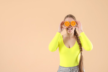 Young woman with orange on color background. Diet concept