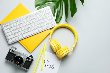 Computer keyboard with notebook, headphones and photo camera on light background