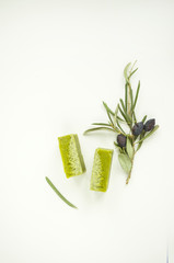 An olive branch and handmade olive soap bars on white background with copyspace.