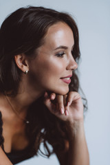 Obraz premium Closeup profile portrait of a brown-eyed brunette woman of 32 years with beautiful healthy hair in a black top on a white background. Soft selective focus.