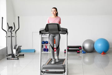 Fototapeta premium Sporty young woman training on treadmill in gym